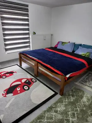 a bedroom with a bed with a blanket and a carpet at Apartman Kenan in Bihać