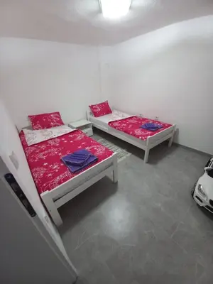 two beds in a room with red and blue sheets at Apartman Kenan in Bihać