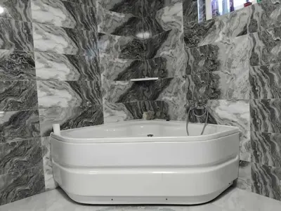 a white tub in a bathroom with marble walls at Apartman Kenan in Bihać