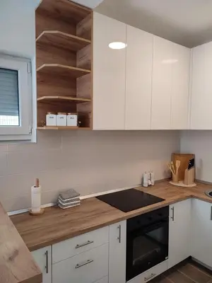 a kitchen with white cabinets and a wooden counter top at Black Forest House in Banja Luka