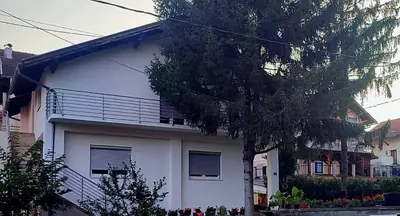 a white house with a tree in front of it at Black Forest House in Banja Luka