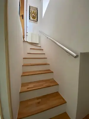 a stairway with white walls and wooden stairs at Apartman ''Trg'' in Tuzla