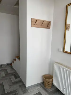 a hallway with white walls and a wooden shelf on the wall at Apartman ''Trg'' in Tuzla
