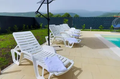 a row of white chairs sitting next to a pool at Villa De Luxe Infinity in Bihać