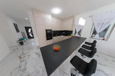 a kitchen with black chairs and a marble floor at Villa De Luxe Infinity in Bihać