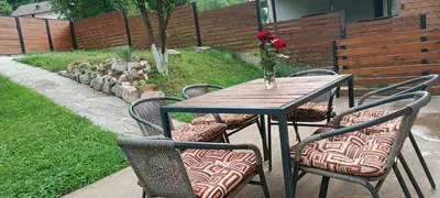 a wooden table with chairs and a vase with roses on it at Pyramid Holiday House in Visoko