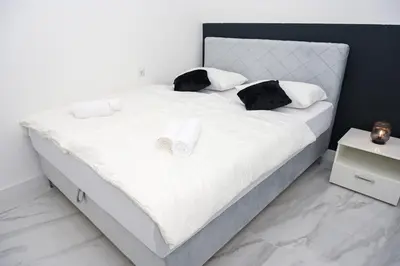 a white bed with two black pillows on it at Apartman Kiko in Jajce