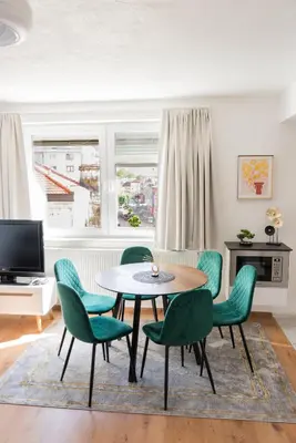 a living room with a table and green chairs at Apartment Center Korzo in Bihać