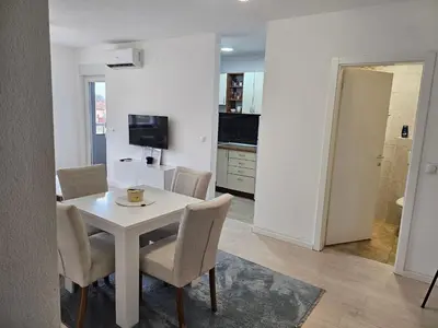 a dining room with a white table and chairs at Apartman Aura in Bosanska Gradiška
