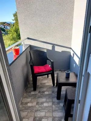 a chair with a red pillow sitting on a balcony at Apartman Aura in Bosanska Gradiška