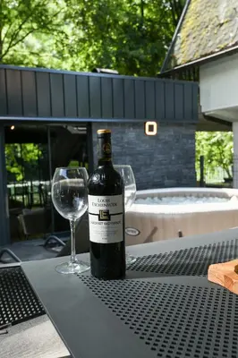 a bottle of wine sitting on a table with a wine glass at Vikendica Villa Natasa in Banja Luka