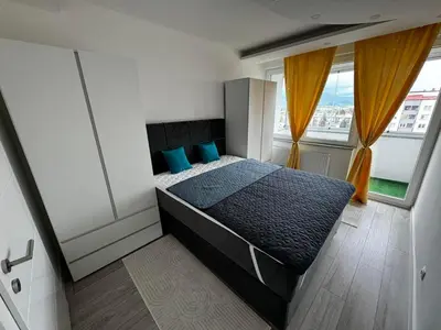 a bedroom with a bed with blue pillows and a window at Asya Art in Bihać