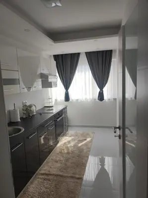 a white kitchen with a sink and a window at Asya Art in Bihać