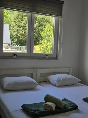 two beds in a room with two windows at Seosko domaćinstvo Bajbut in Bihać