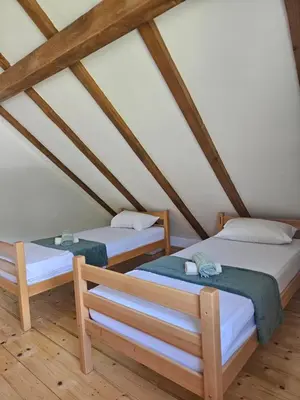 two beds in a attic room with wooden beams at Seosko domaćinstvo Bajbut in Bihać