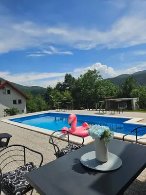 a pool with a table and chairs and a pink inflatable at Seosko domaćinstvo Bajbut in Bihać
