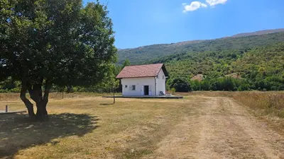 a small white house in a field with a tree at Livanjsko Polje Cottage #14 in Lusnić