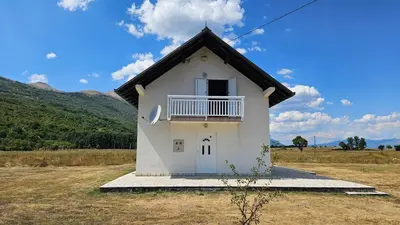a small white house with a balcony on a field at Livanjsko Polje Cottage #14 in Lusnić