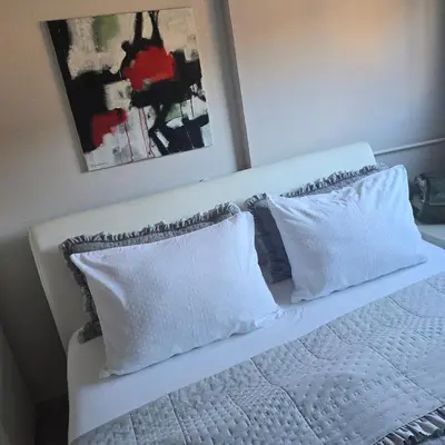 a white bed with two pillows and a painting at Alex Bl in Banja Luka