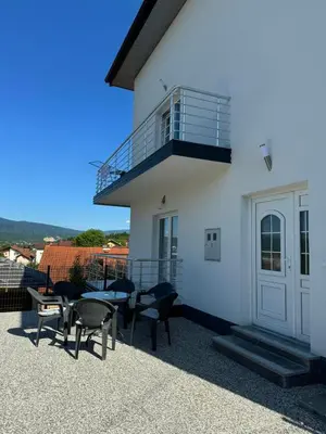 a white building with chairs and tables and a balcony at Apartment BORICI in Bihać