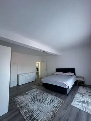 a white bedroom with a bed and a rug at Apartment BORICI in Bihać