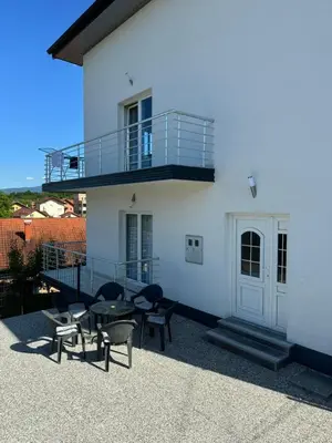 a white building with a balcony and a table and chairs at Apartment BORICI in Bihać