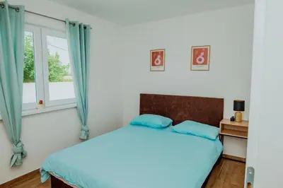 a bedroom with a bed with blue pillows and a window at Kuća za odmor Vučjak in Bihać