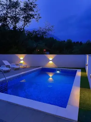 a swimming pool in a backyard at night with lights at Kuća za odmor Vučjak in Bihać