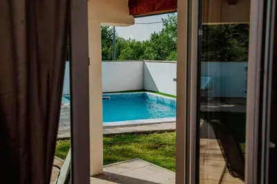 a view of a swimming pool through a sliding glass door at Kuća za odmor Vučjak in Bihać