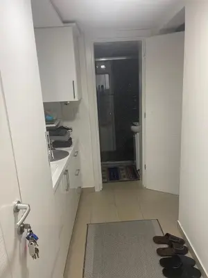a hallway with a door to a kitchen with shoes on the floor at Apartmani Teša in Tešanj