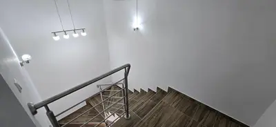 a staircase with a metal rail and a white wall at Apartmani Teša in Tešanj