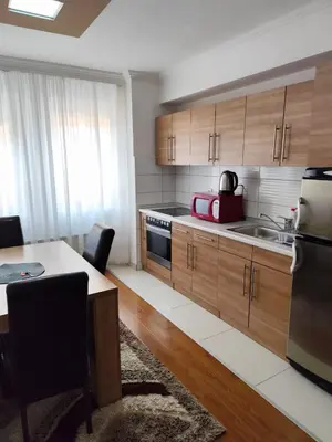 a kitchen with wooden cabinets and a sink and a table at Apartment Stari Grad Korzo Tuzla in Tuzla