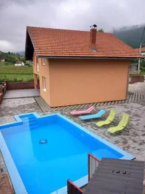 a large blue swimming pool in front of a house at Villa Kula Bihac in Orašac