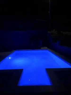 a blue swimming pool lit up in the dark at Villa Kula Bihac in Orašac
