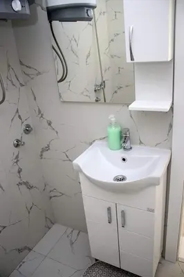 a white bathroom with a sink and a mirror at Vikendica Gajić in Šipovo