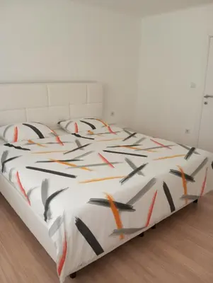 a white bed with orange and black pillows on it at Apartmani Mušinbegović in Visoko