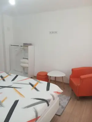 a room with a bed and a red chair at Apartmani Mušinbegović in Visoko