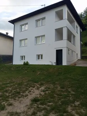 a white house with a large yard in front of it at Apartmani Mušinbegović in Visoko