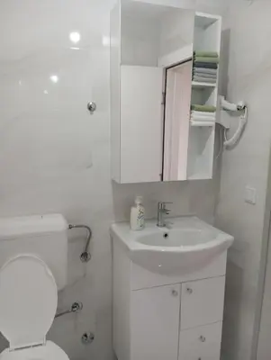 a white bathroom with a toilet and a sink at Apartmani Mušinbegović in Visoko