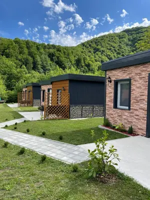 a house with a mountain in the background at Bungalovi Izvor Plive in Šipovo