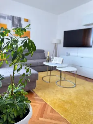 a living room with a couch and two tables and a plant at Appartement Nada in Bosanski Brod