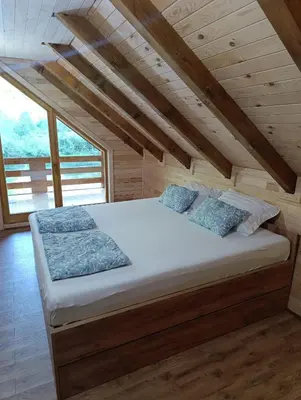 a large bed in a room with wooden ceilings at Vikendica Ana in Šipovo