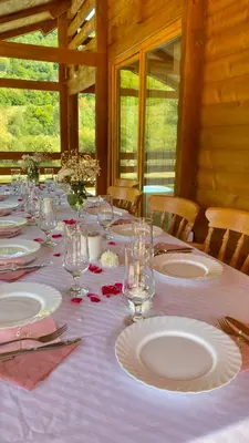 a long table with white plates and wine glasses at Vikendica Ana in Šipovo