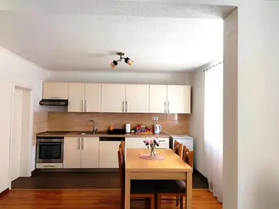 a kitchen with white cabinets and a table with flowers on it at Apartman Dream in Livno