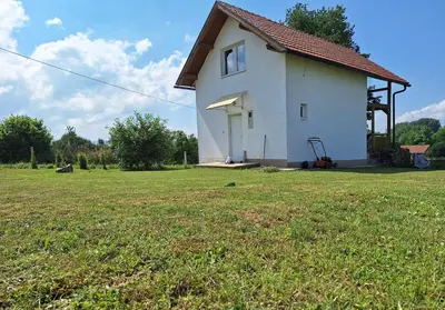 a small white house with a large grass field at GREEN MOON Breza in Breza