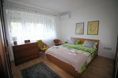 a bedroom with a bed and a desk and a window at Apartman Mak in Bihać