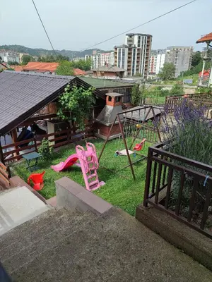 a backyard with a playground with pink chairs in the grass at Apartmani Nadi in Tuzla