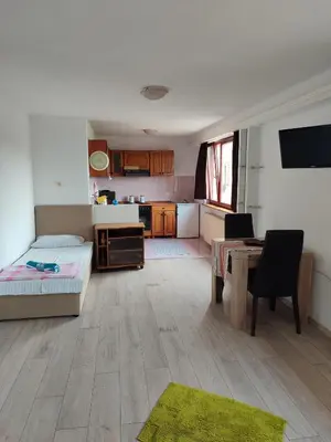 a room with a bed and a table and a kitchen at Apartmani Nadi in Tuzla