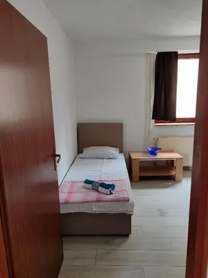 a small bedroom with a bed and a window at Apartmani Nadi in Tuzla
