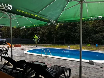 a swimming pool with chairs and a green umbrella at Jerry's Forest in Banja Luka